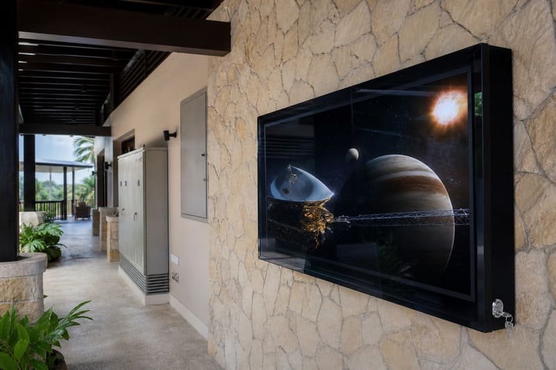 65-inch poolside TV enclosure positioned above splash exposure with shade, clear airflow, protected cable routing, guest circulation space, and staff service access
